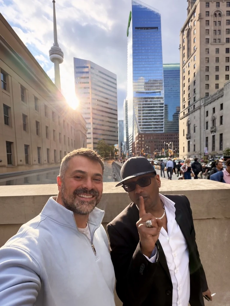 Martin Vassilev and Khalid Mohamed taking a selfie in downtown Toronto, with the CN Tower and office towers behind them